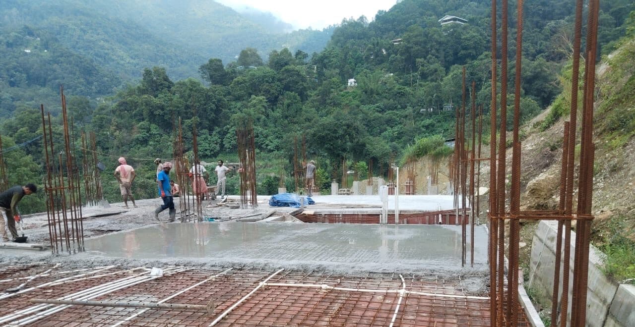 A floor slab freshly poured, the next bay's steel already laid